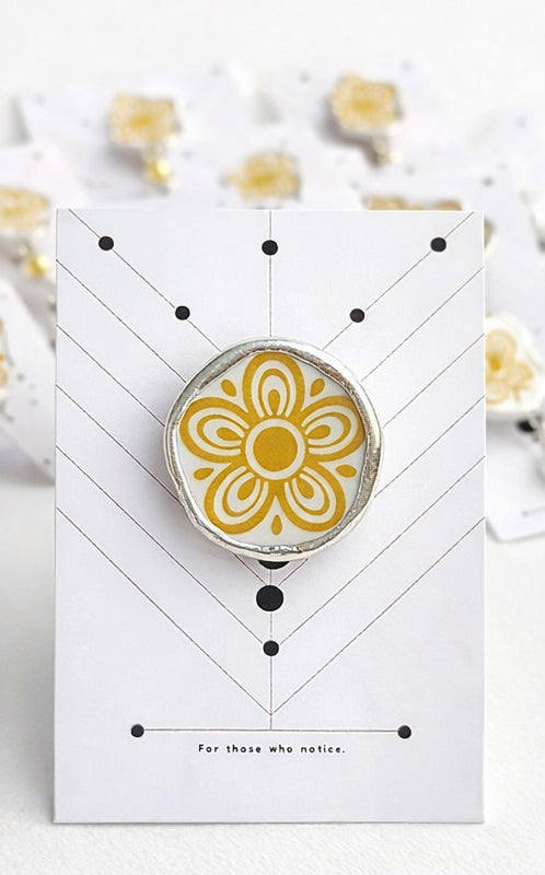 Yellow flower-shaped object on a white card with geometric design