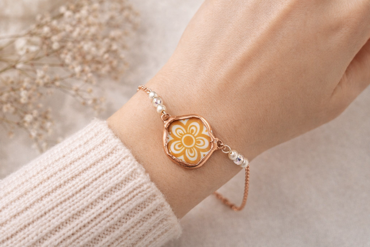 Bracelet with a floral design on a wrist, against a neutral background
