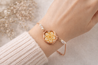 Bracelet with a floral design on a wrist, against a neutral background