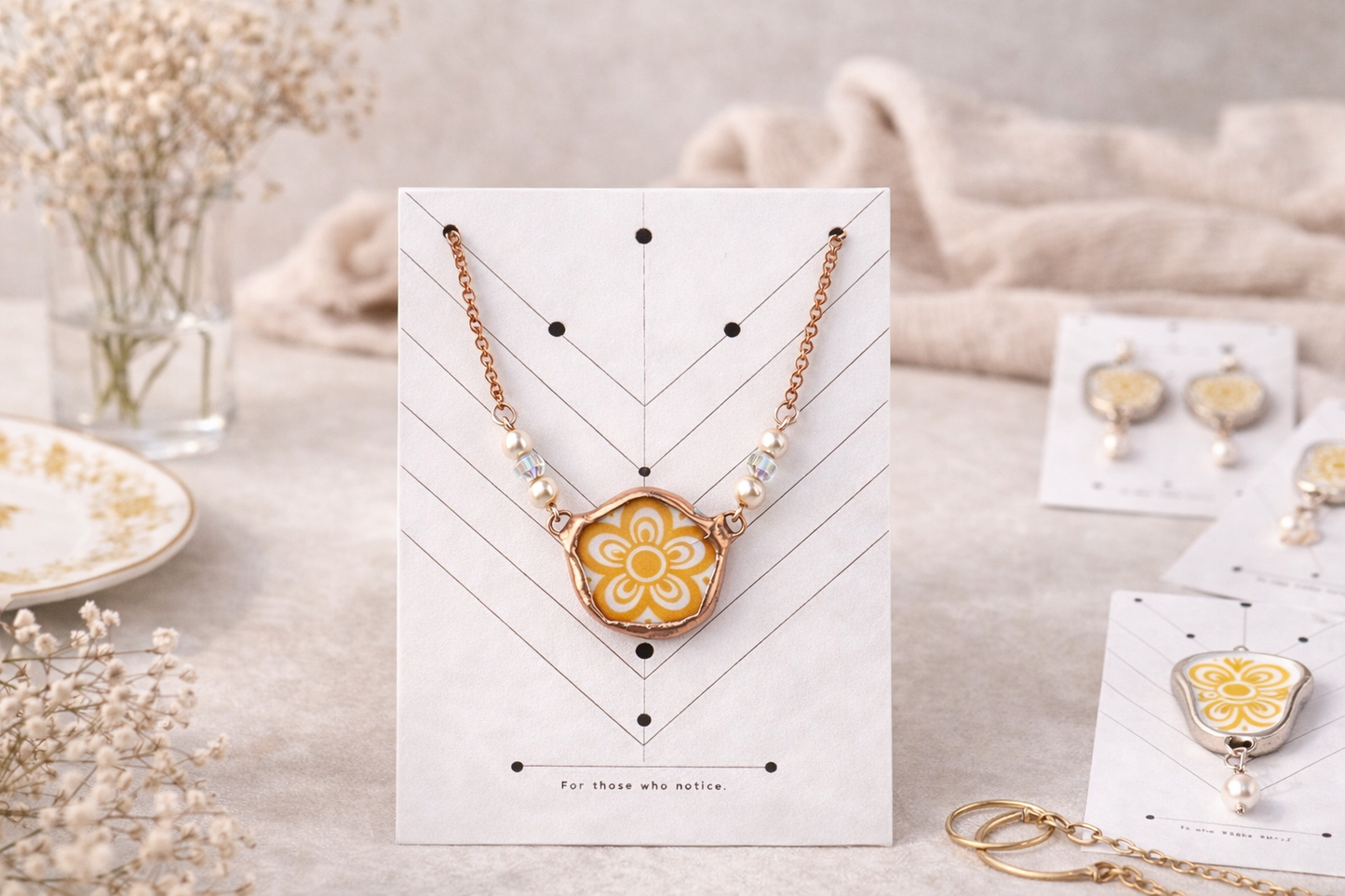 Necklace with a yellow floral design on a white card, surrounded by other jewelry items.