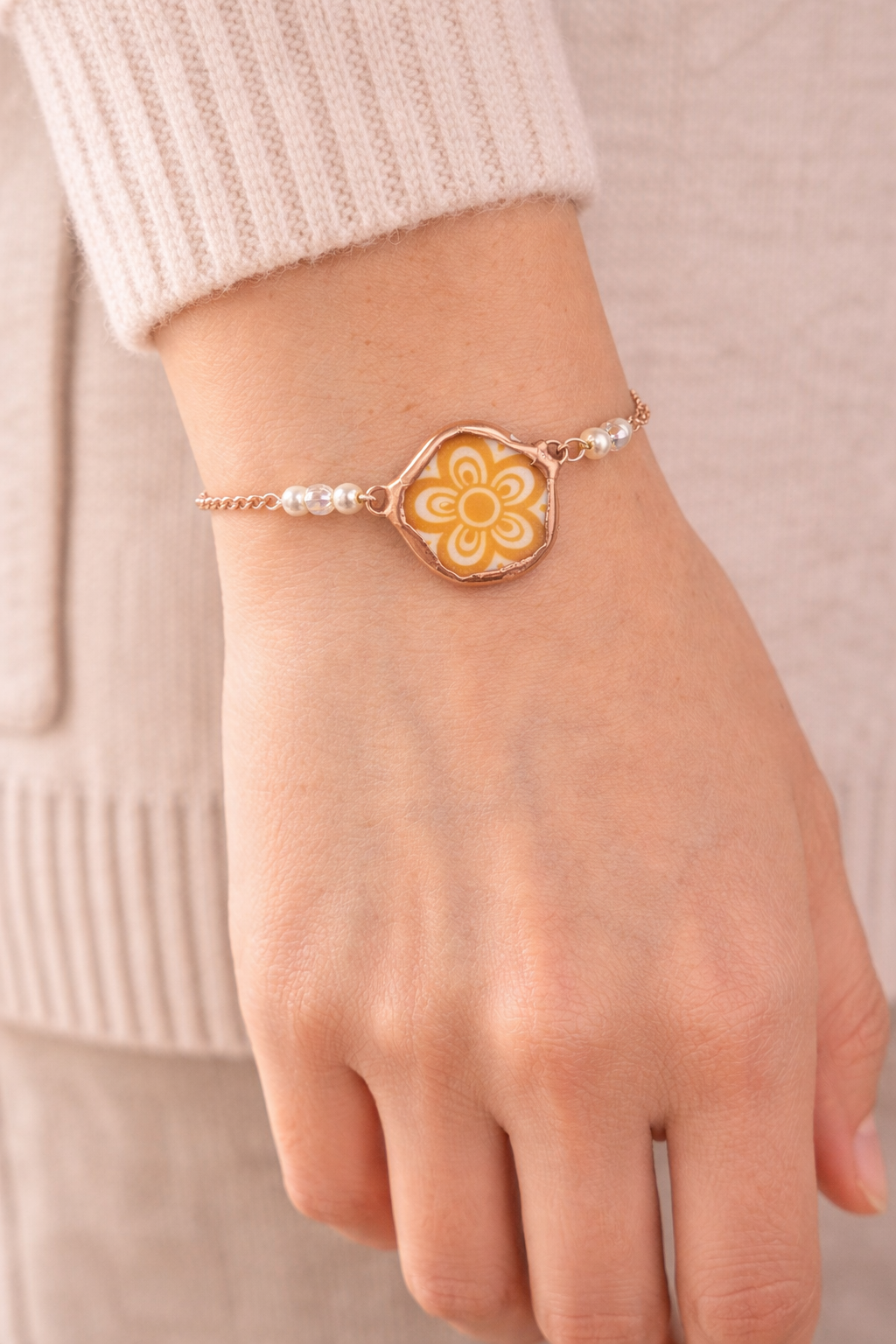 Bracelet with a floral design on a wrist against a neutral background